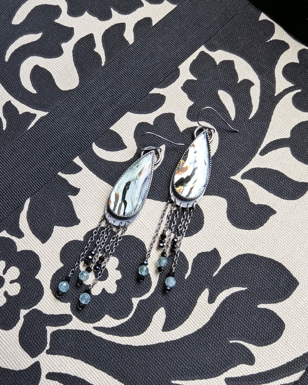 Sterling silver earrings with long chain fringe, green apatite, and black spinel beads on fabric
