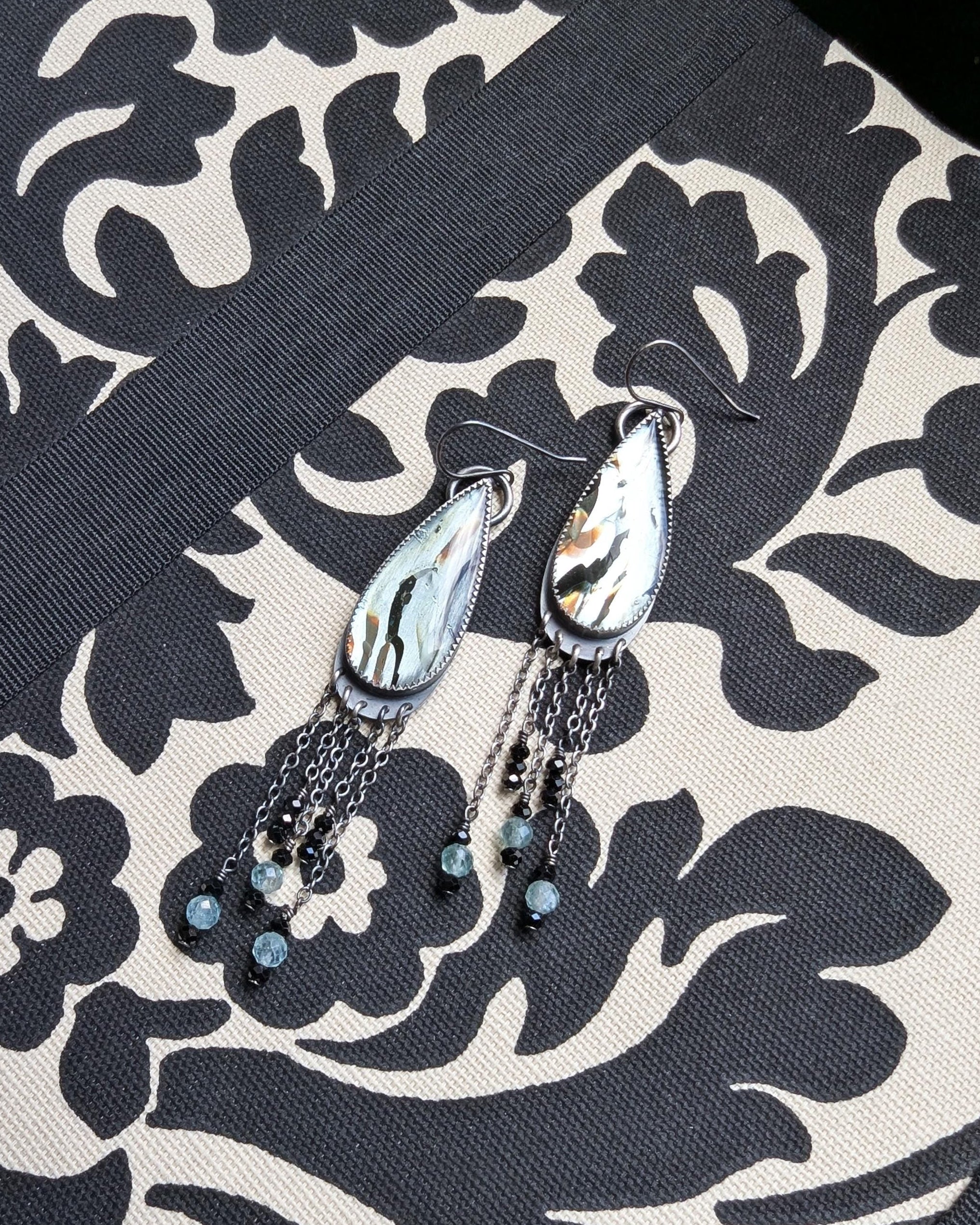 Sterling silver earrings with long chain fringe, green apatite, and black spinel beads on fabric
