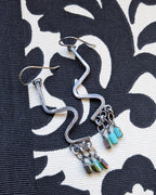 Serpentine-inspired silver earrings with multicolor crystal shimmer