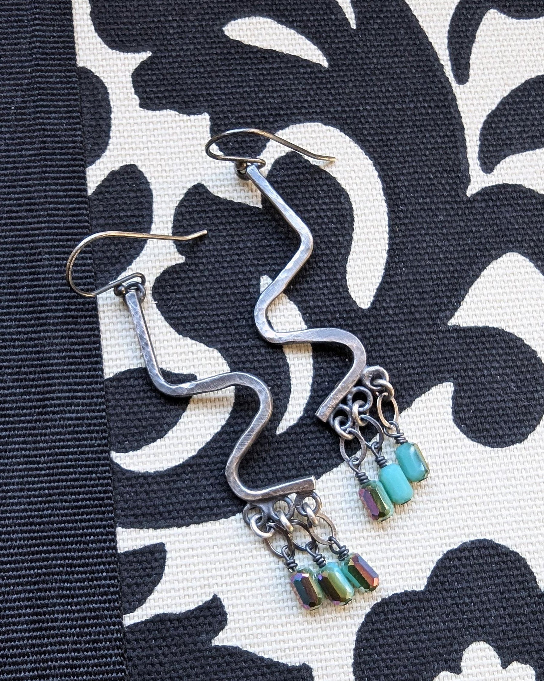 Serpentine-inspired silver earrings with multicolor crystal shimmer