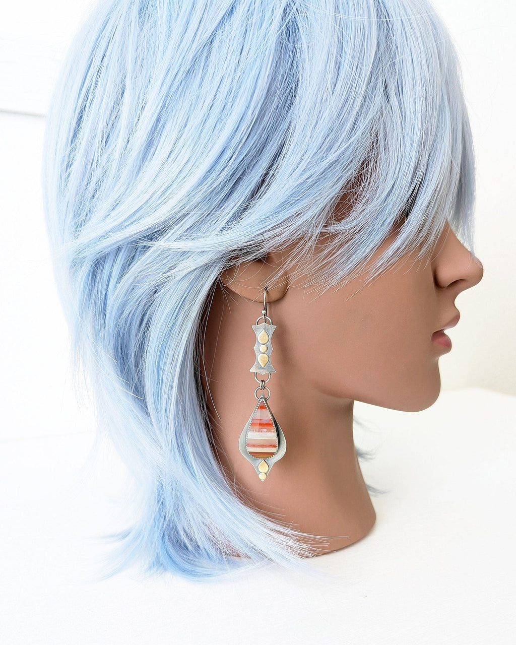 Earthy statement earrings with warm brass and oxidized silver contrast on mannequin for scale