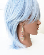 Earthy statement earrings with warm brass and oxidized silver contrast on mannequin for scale