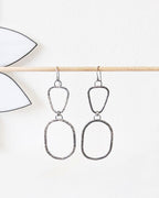 Silver earrings hanging on a stick.