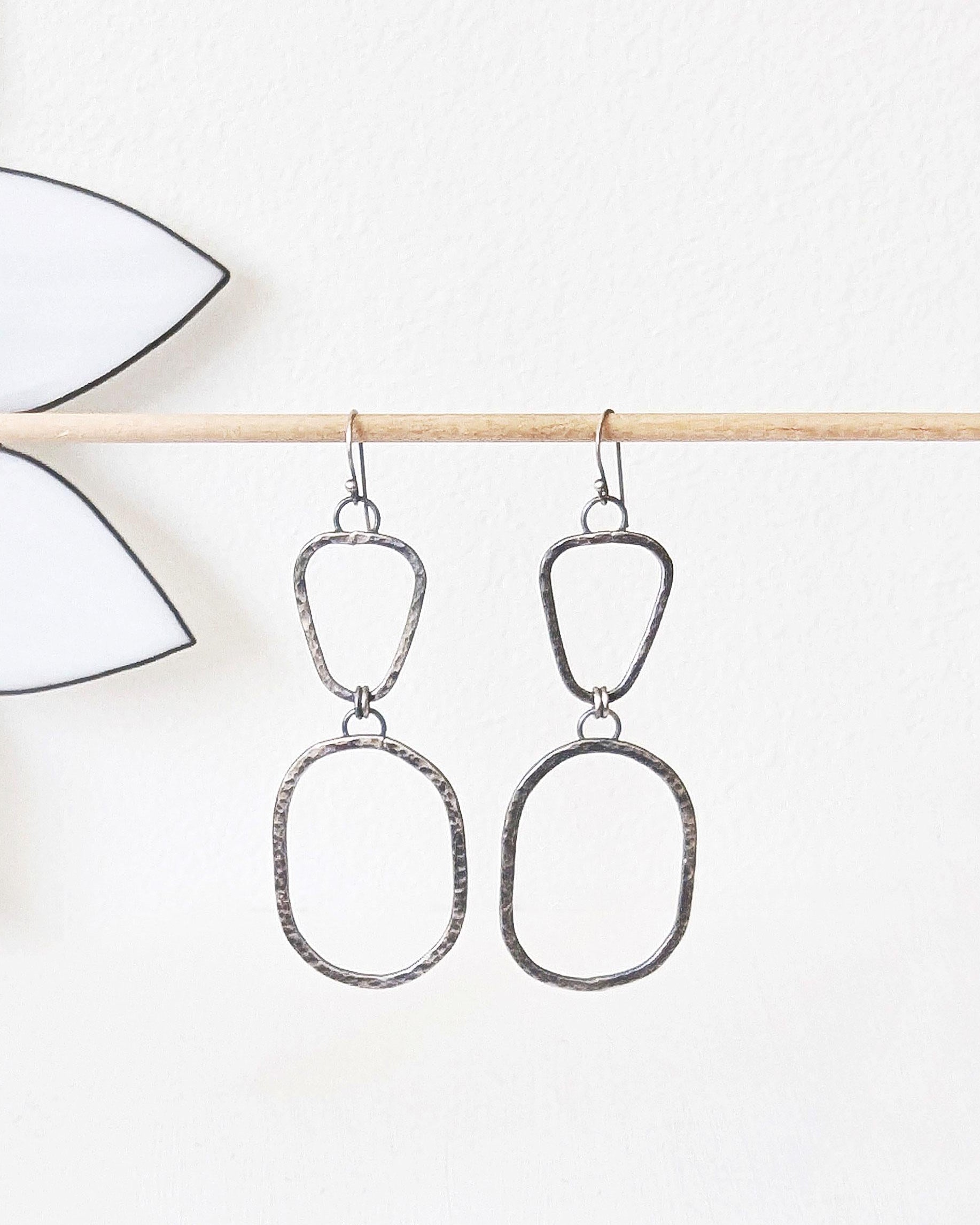 Silver earrings hanging on a stick.