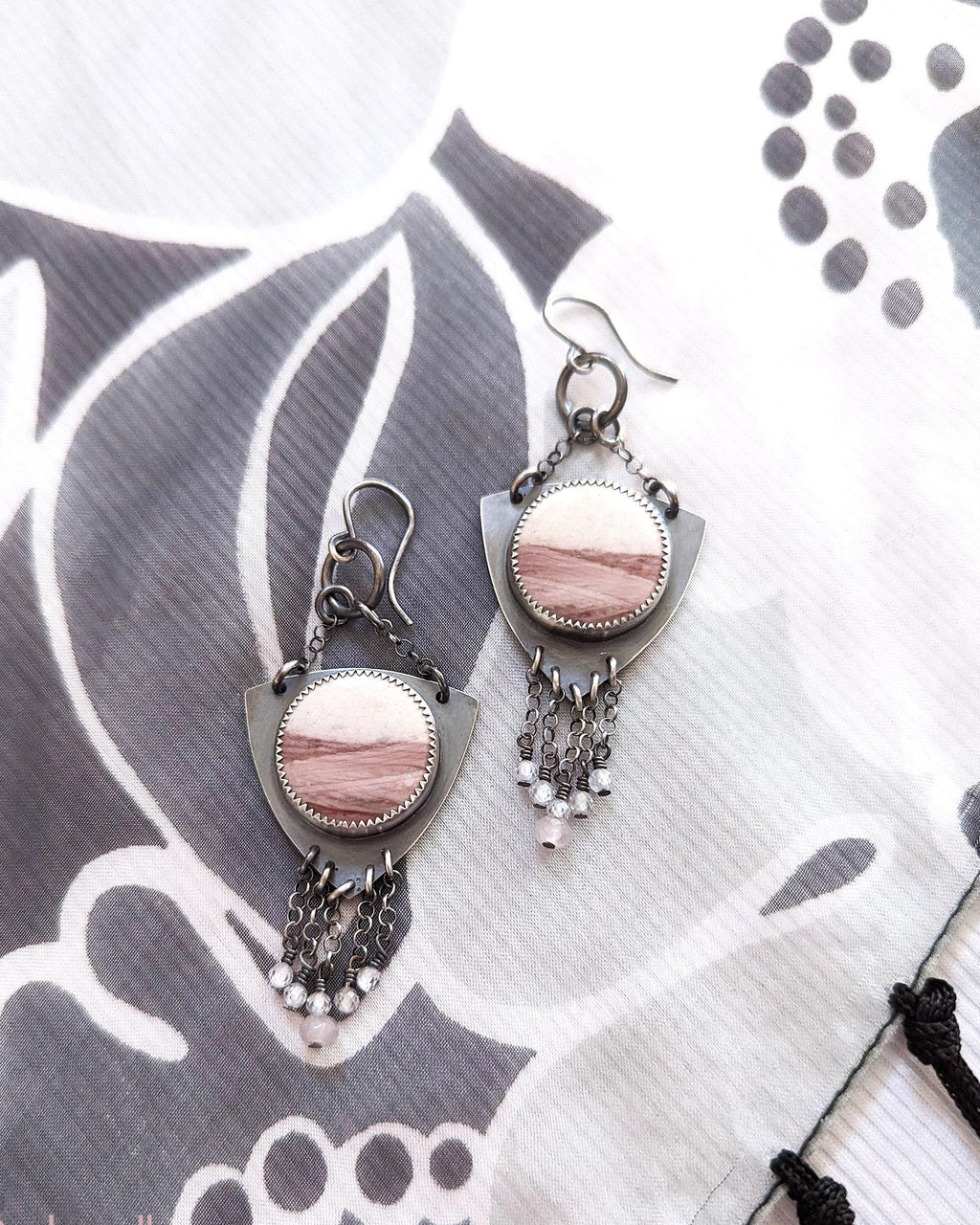 Pair of earrings with pink stones on a patterned fabric background