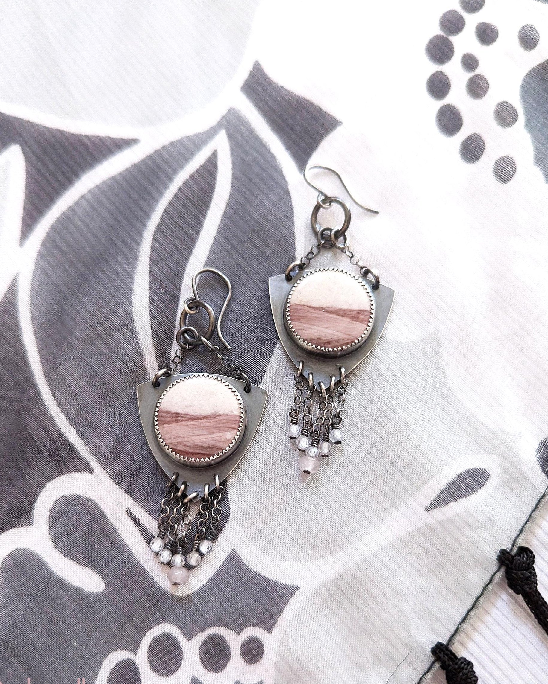 Pair of earrings with pink stones on a patterned fabric background