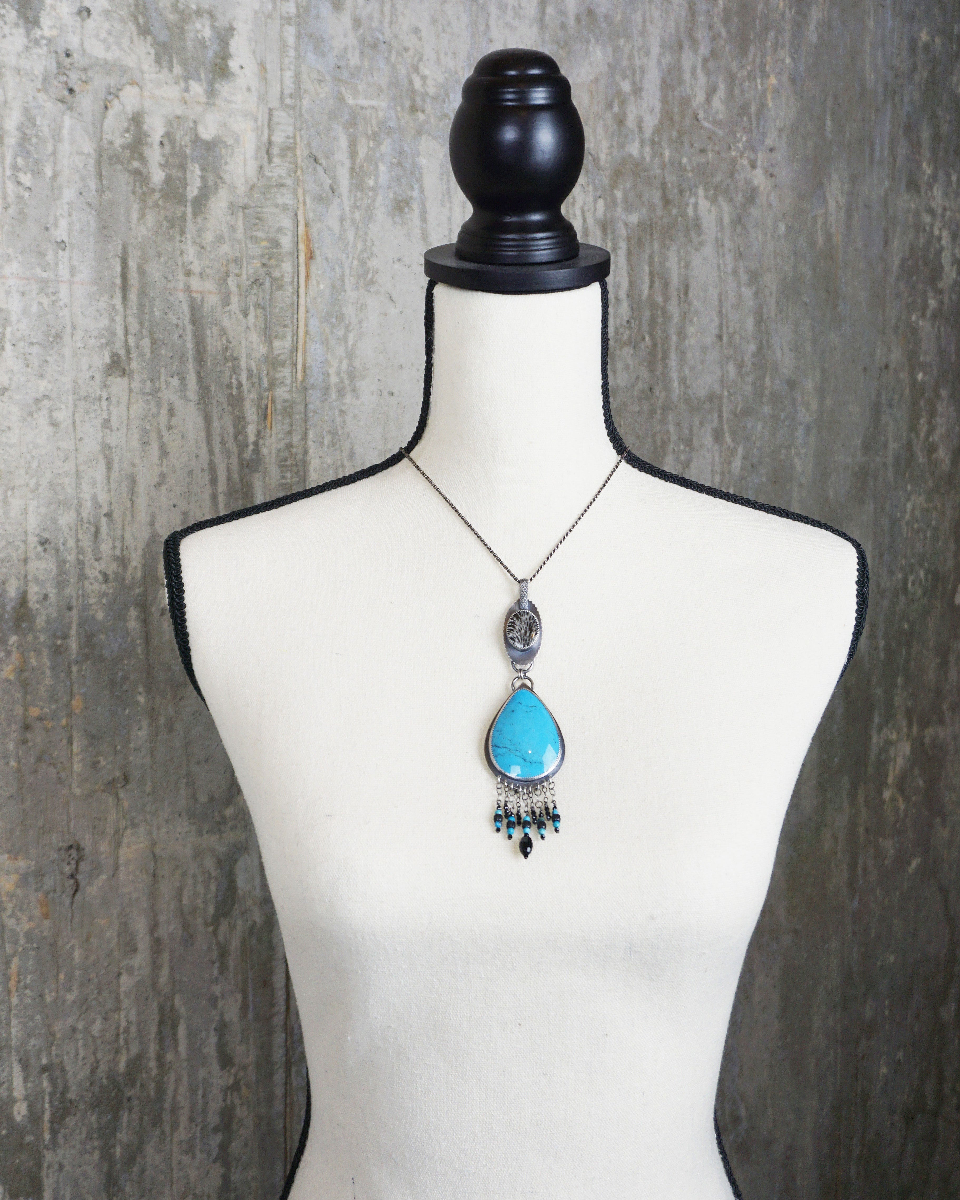 bold turquoise statement necklace with black and white coral detail on bust for scale