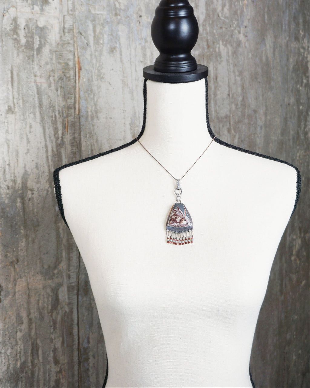 handcrafted silver pendant with earthy rhyolite design on bust for scale (chain not included)