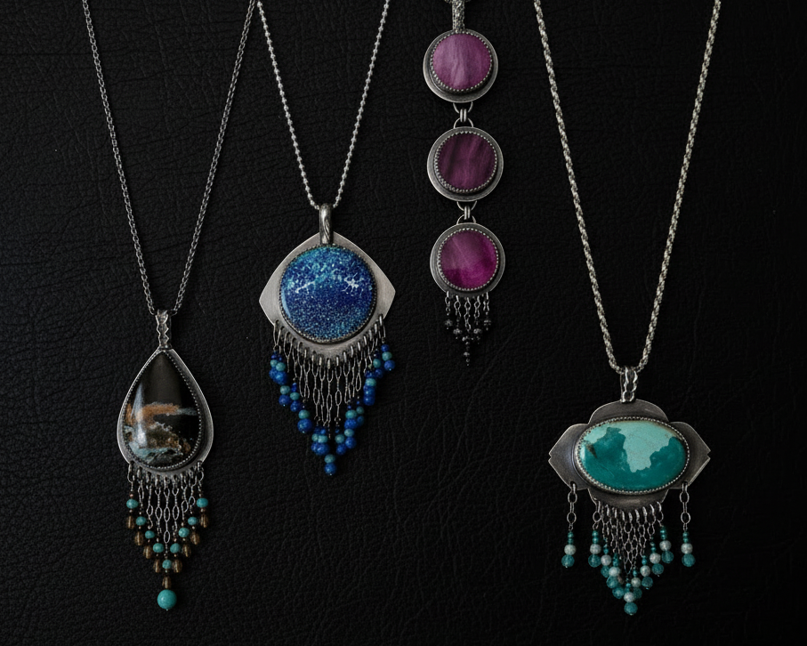 Four necklaces with unique Rebellenhaus pendants on a black background