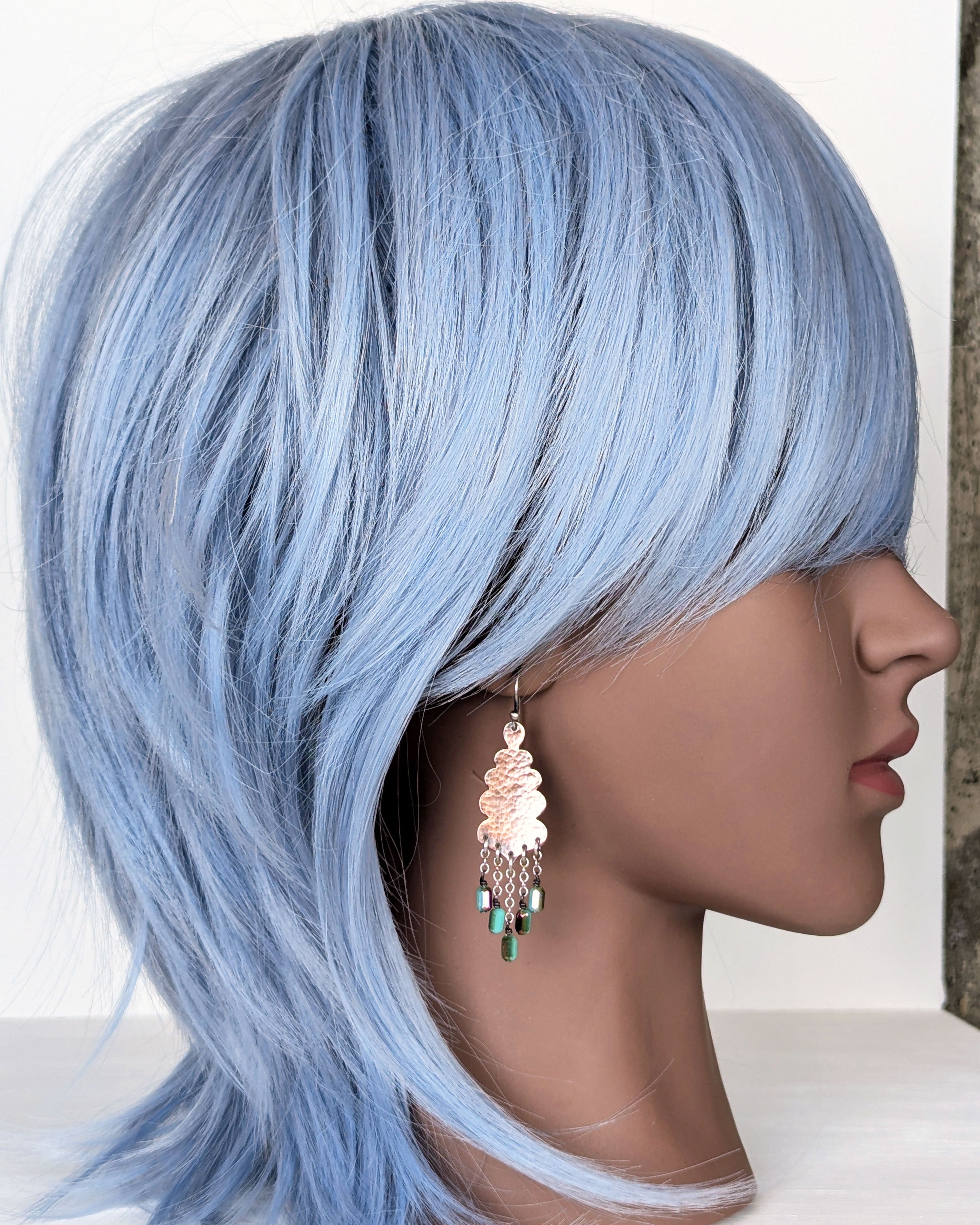 southwestern copper earrings with turquoise green and magenta flashes on mannequin for scale