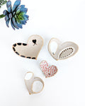 Rustic handmade ceramic heart jewelry dishes displayed together, artisan stoneware catchall bowls for earrings, watches, coins, and keepsakes.