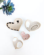 Rustic handmade ceramic heart jewelry dishes displayed together, artisan stoneware catchall bowls for earrings, watches, coins, and keepsakes.