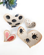 Four handmade ceramic heart dishes with unique painted patterns in rustic stoneware clay.