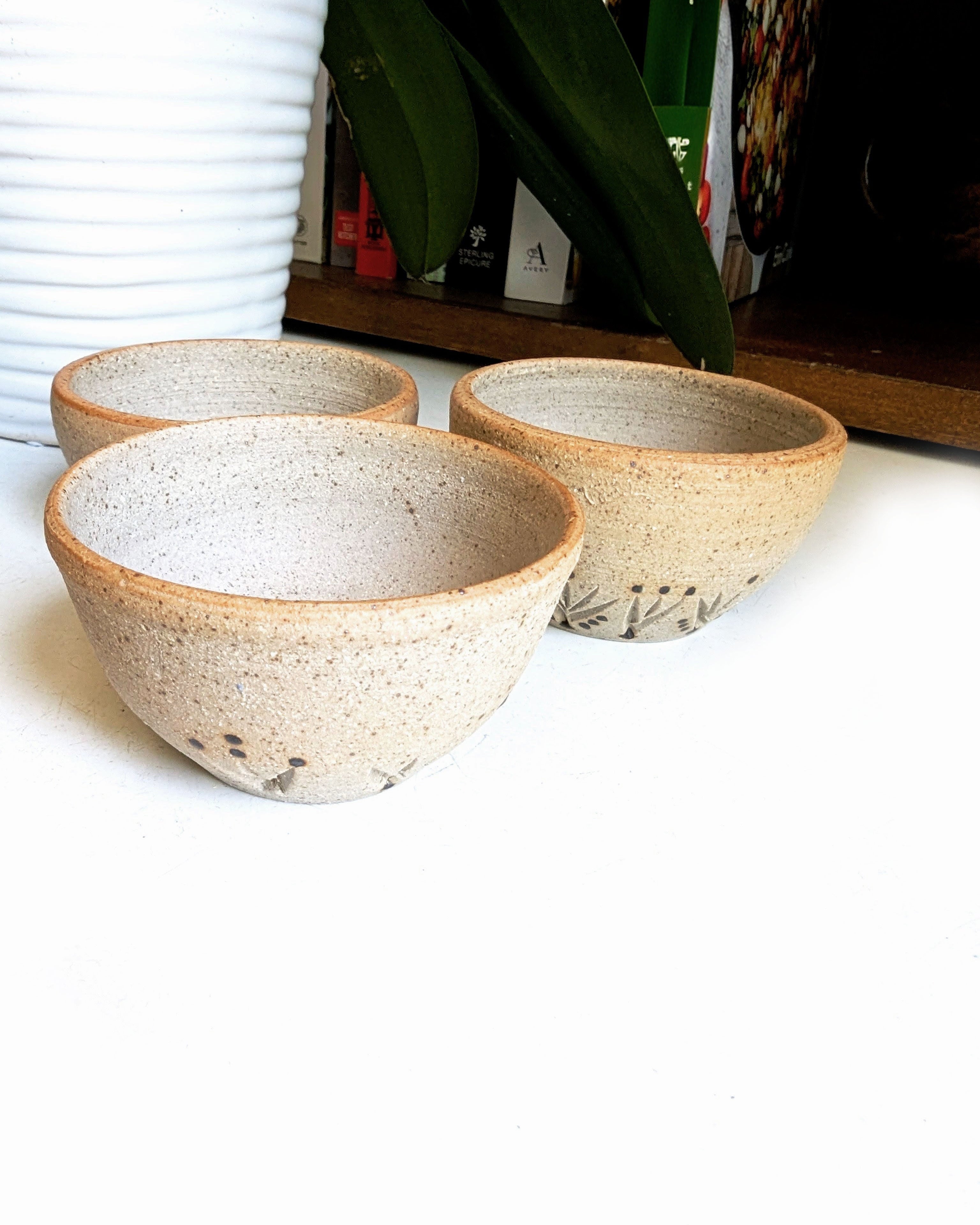 Hand-painted stoneware catchall bowls with warm natural clay and bold carved Southwestern patterns.