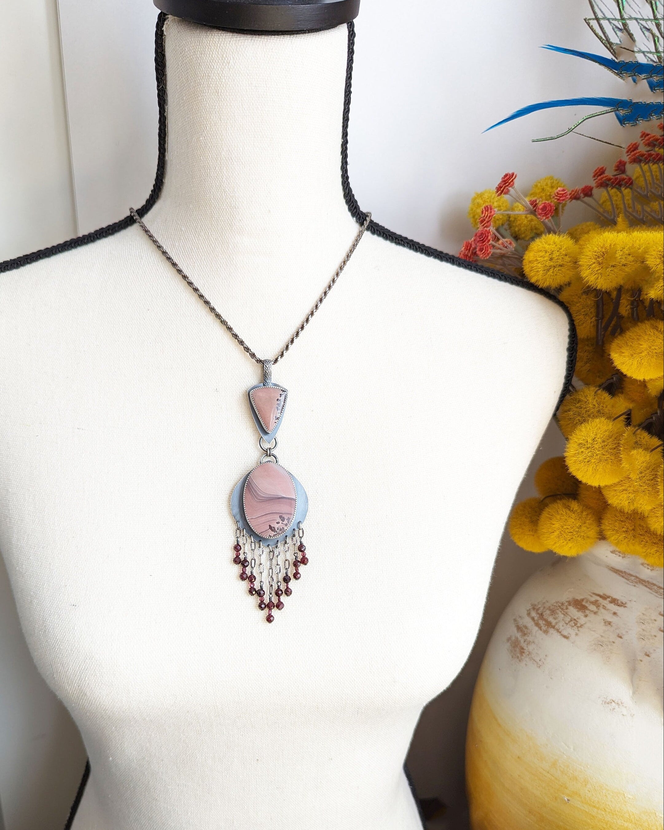 Desert-inspired gemstone pendant with sparkling garnet detail on bust for scale