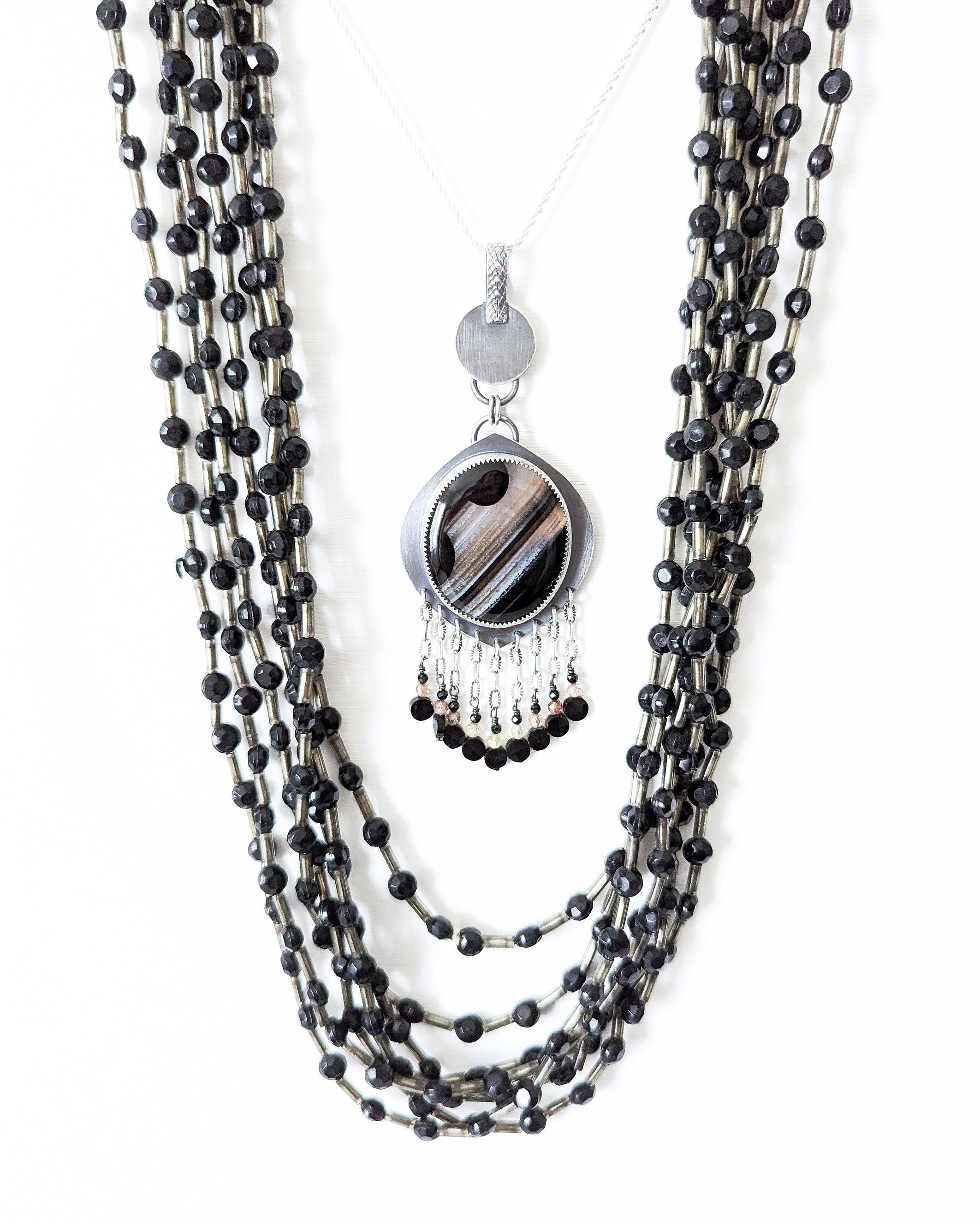 Round black banded agate pendant with leaf-shaped oxidized silver frame