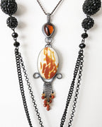 Necklace with black beads and a central pendant on a white background