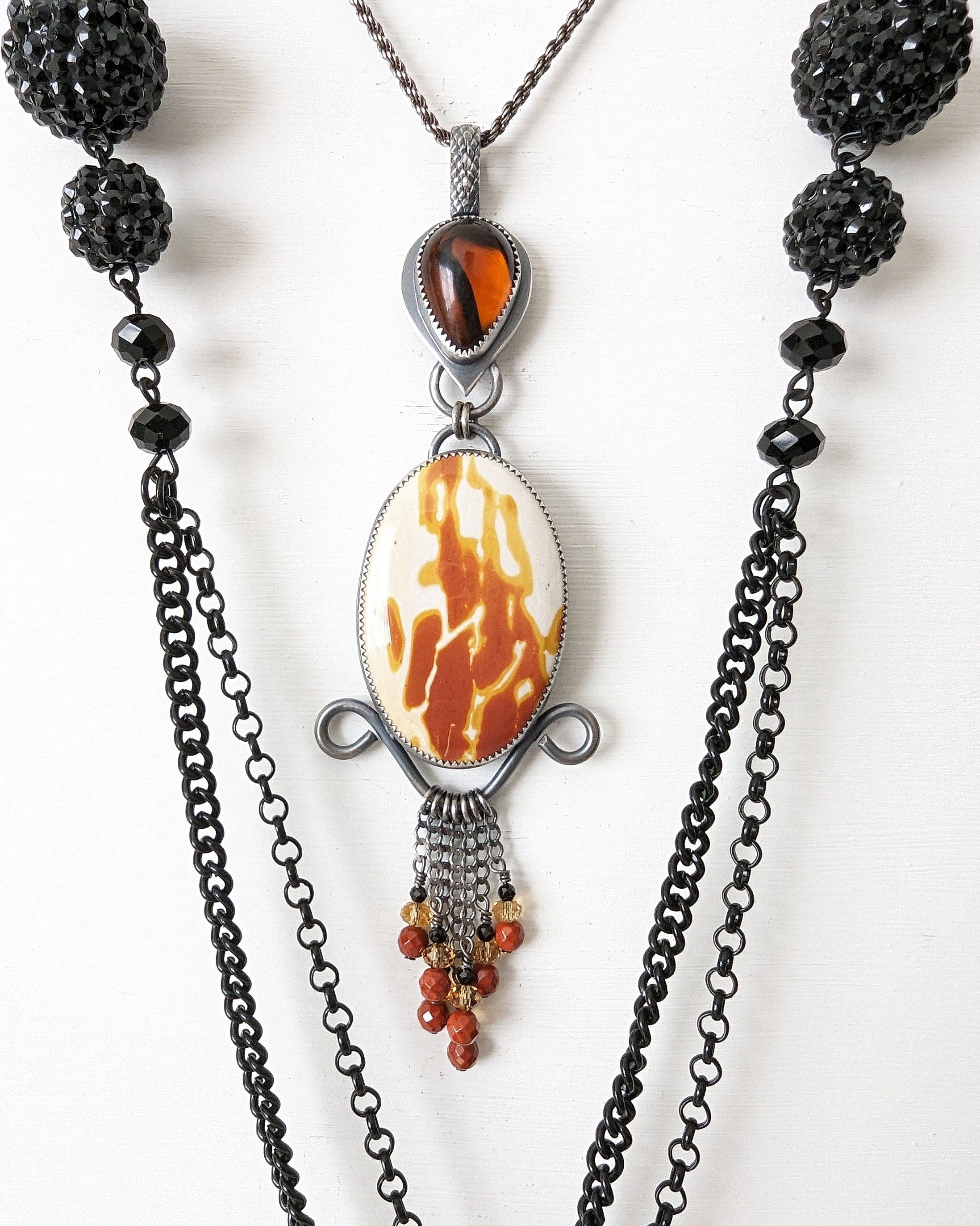 Necklace with black beads and a central pendant on a white background