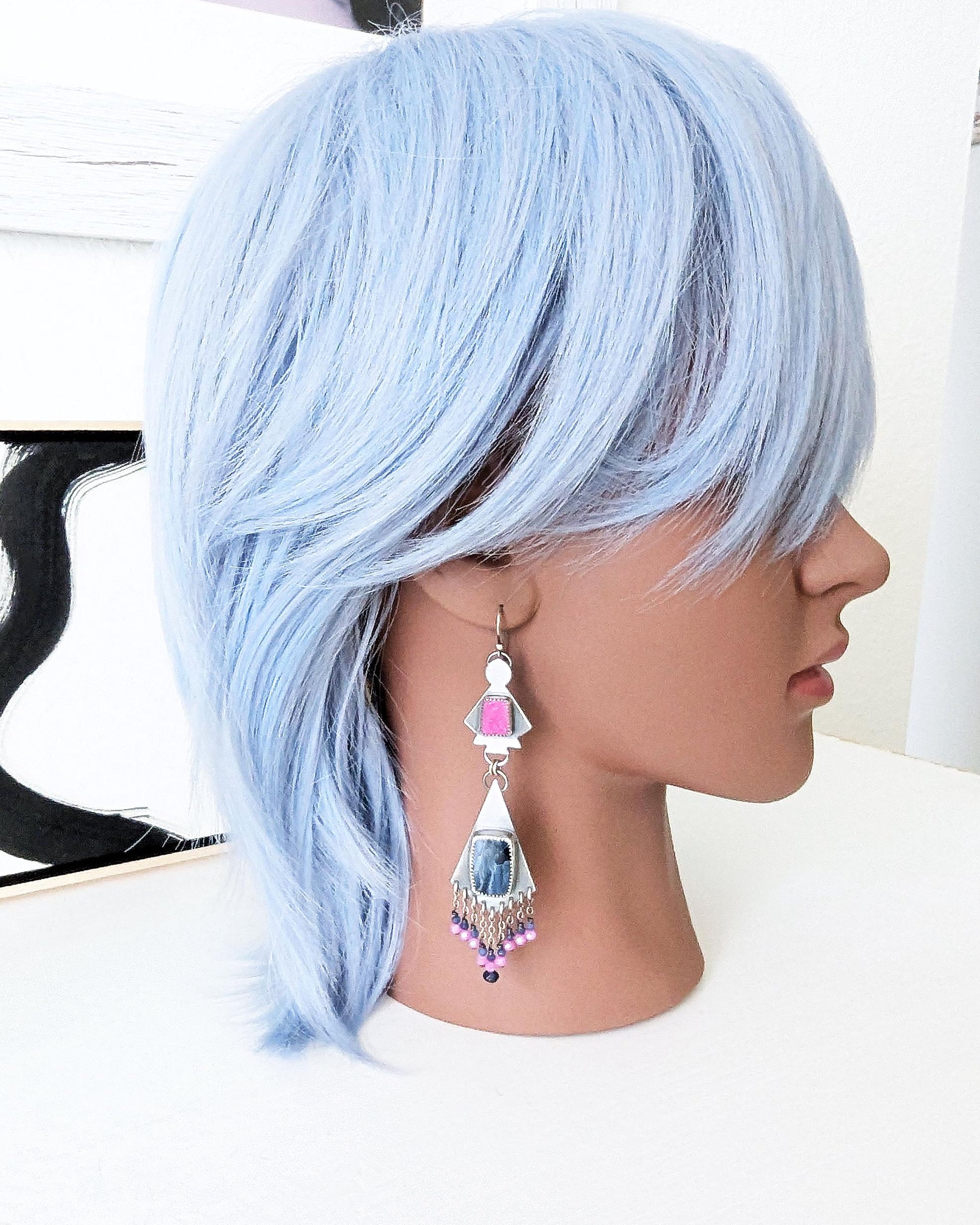 Luxury artisan earrings featuring pietersite and calcite on mannequin for scale