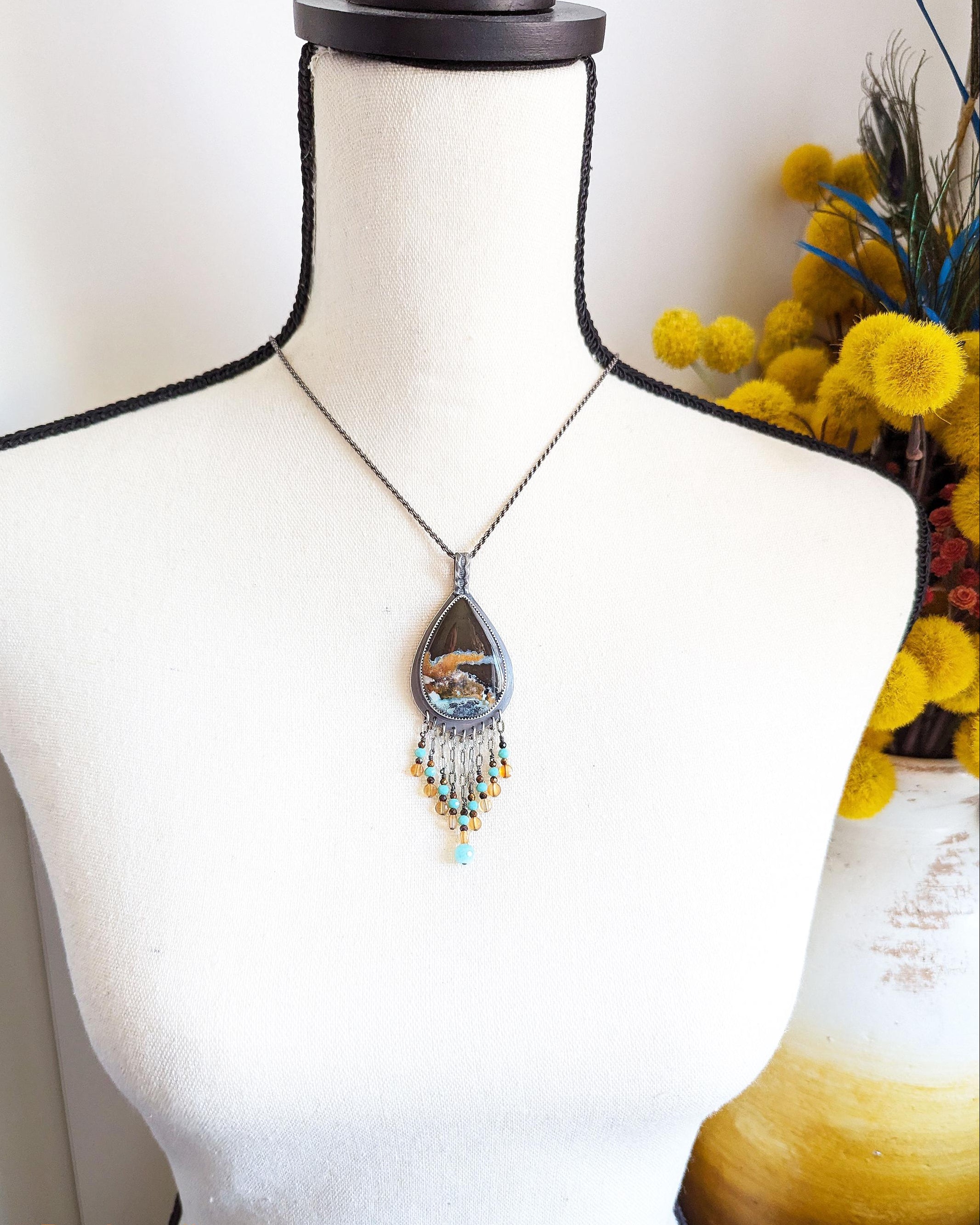 Collector gemstone pendant featuring opalized wood and mixed stone accents shown on bust for scale
