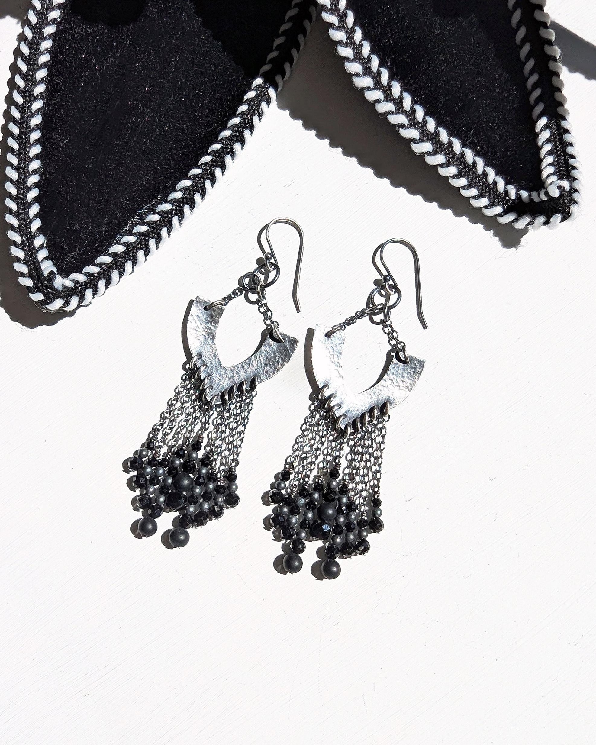 Black beaded earrings on a white background with hammered sterling silver horseshoe elements