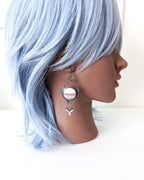 Mannequin head with light blue hair and silver earring on a white background