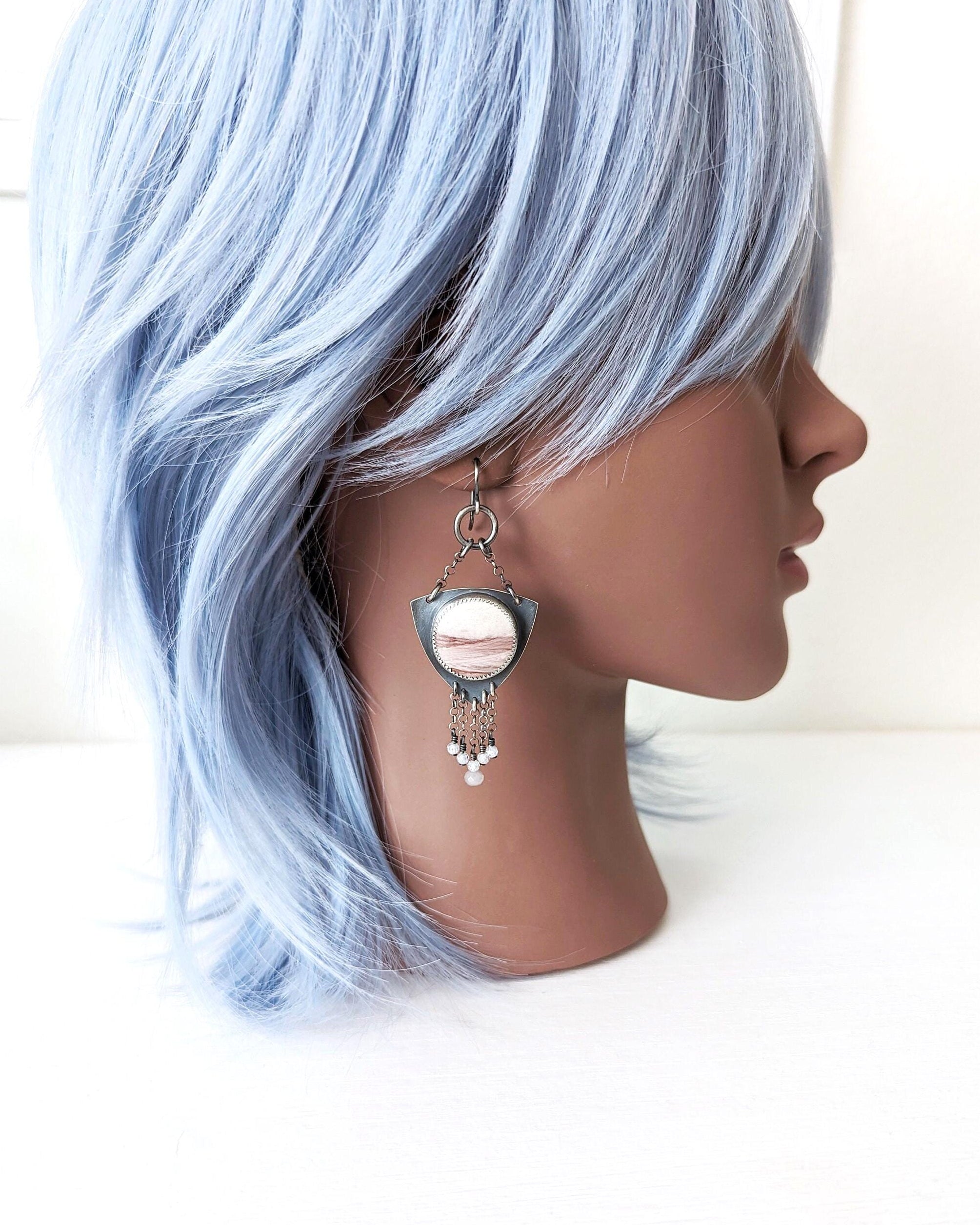 Mannequin head with light blue hair and silver earring on a white background