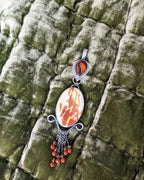 Jewelry pendant with a stone and beads on a textured green fabric background