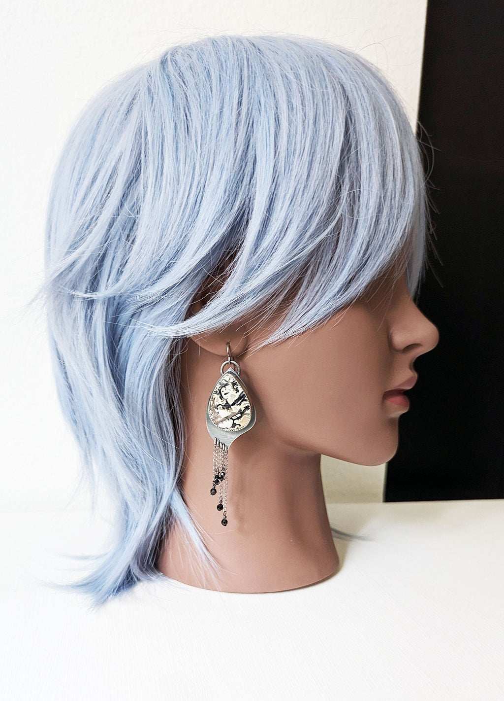 Nature-inspired gemstone earrings with asymmetrical movement on mannequin for scale