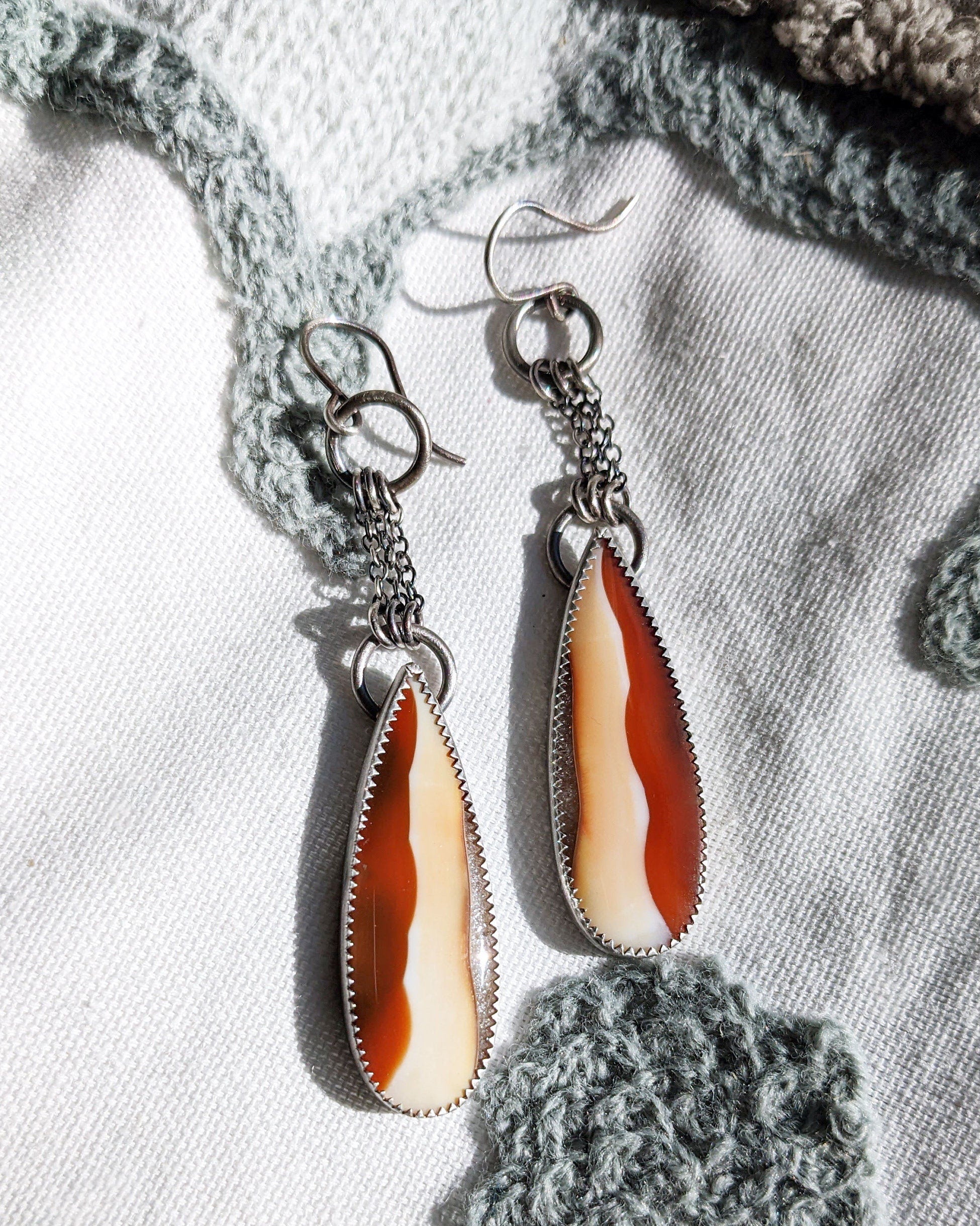 Dramatic chain fringe earrings with warm autumn gemstone tones in natural sunlight