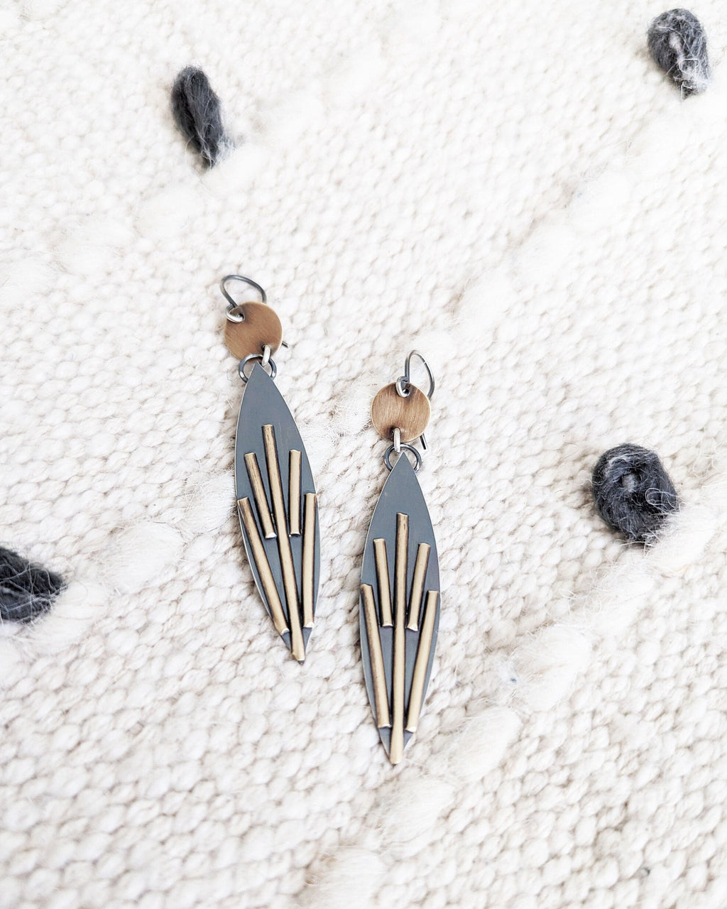 Pair of geometric earrings on a textured white surface.