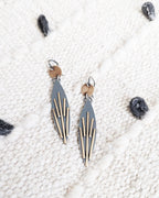 Pair of geometric earrings on a textured white surface.