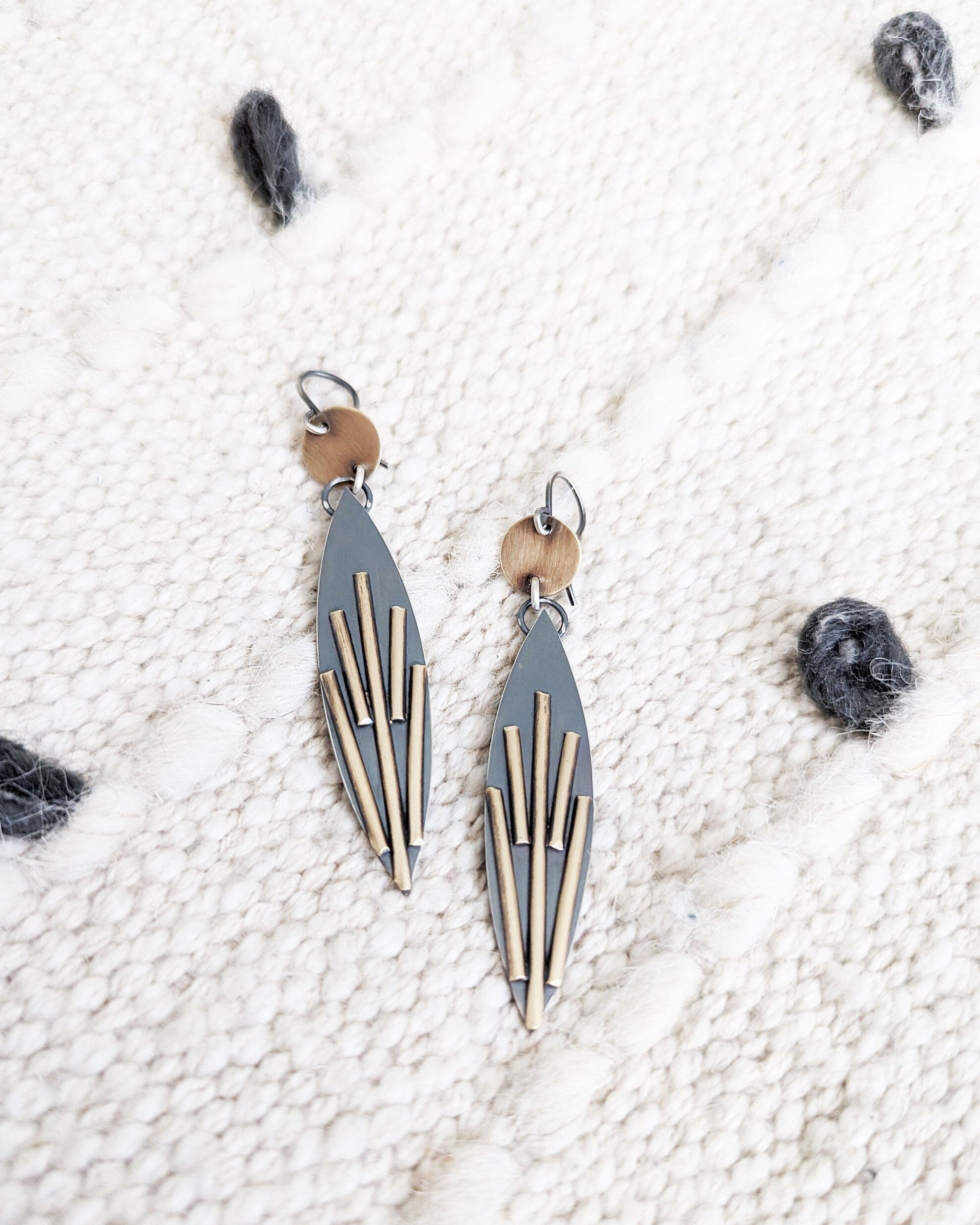 Pair of geometric earrings on a textured white surface.