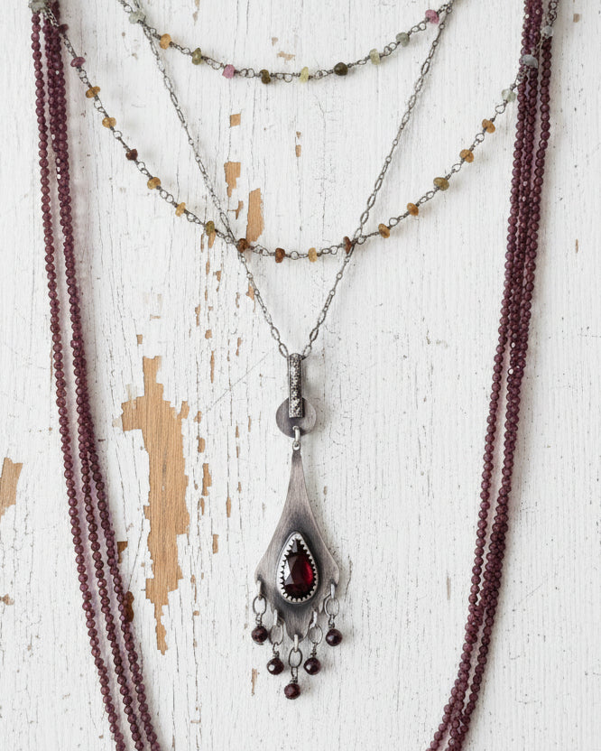 Deep red garnet bead fringe beneath romantic silver setting on chain with layering necklaces (not included)