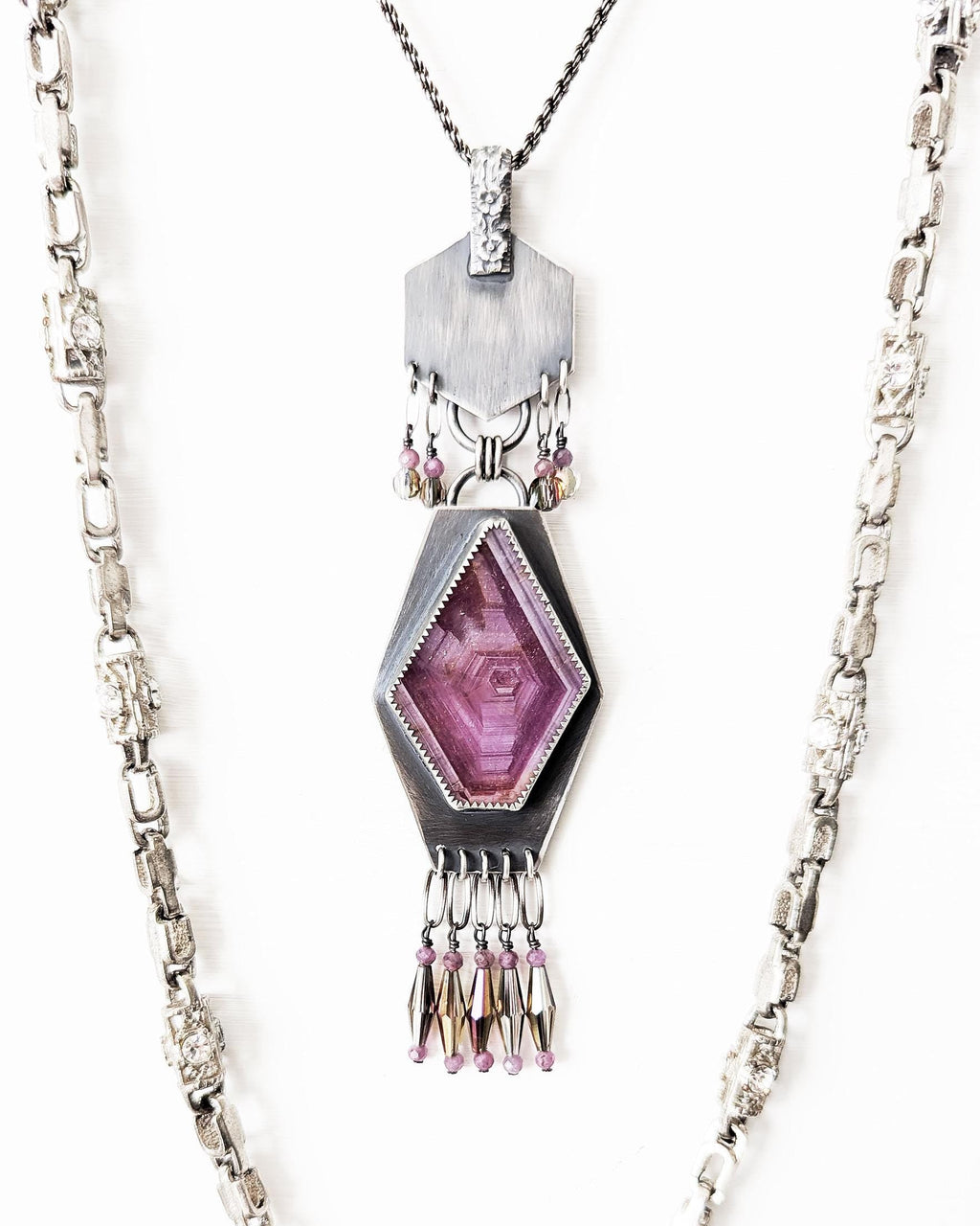 Geometric oxidized sterling silver pendant with raw ruby centerpiece in bright light