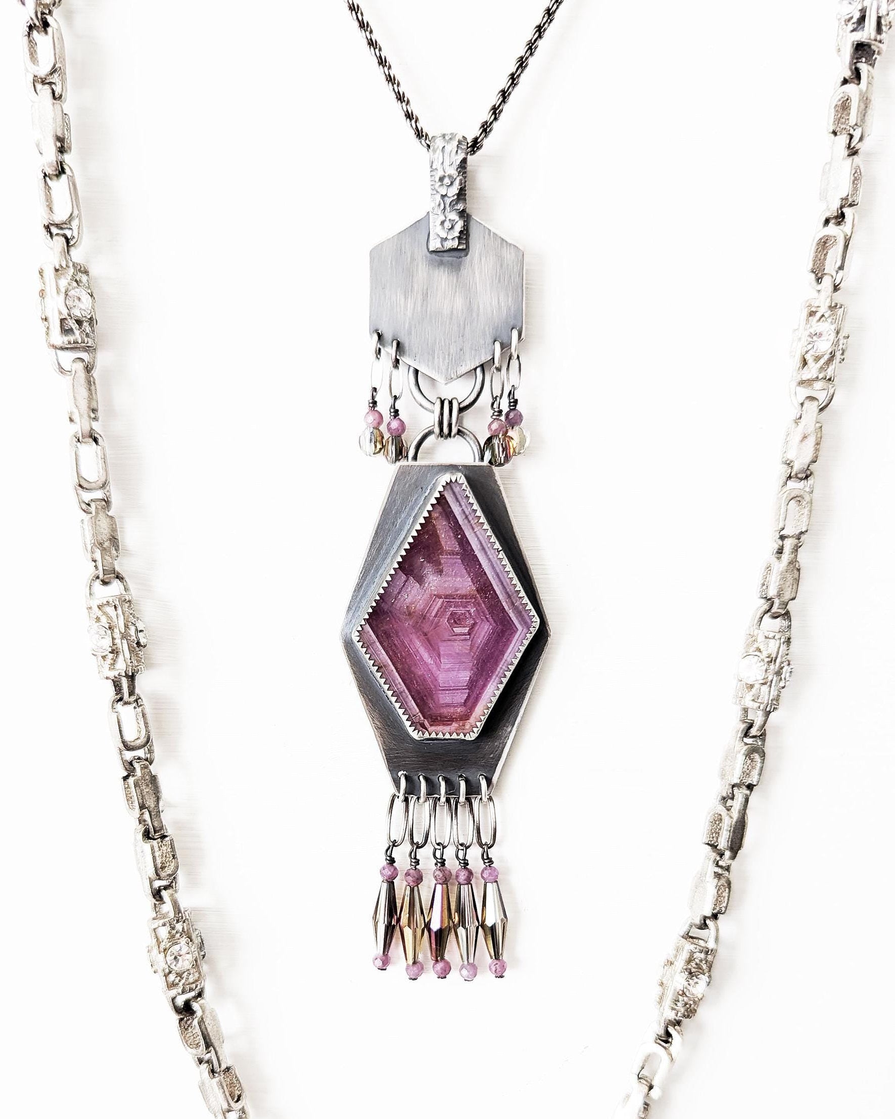 Geometric oxidized sterling silver pendant with raw ruby centerpiece in bright light