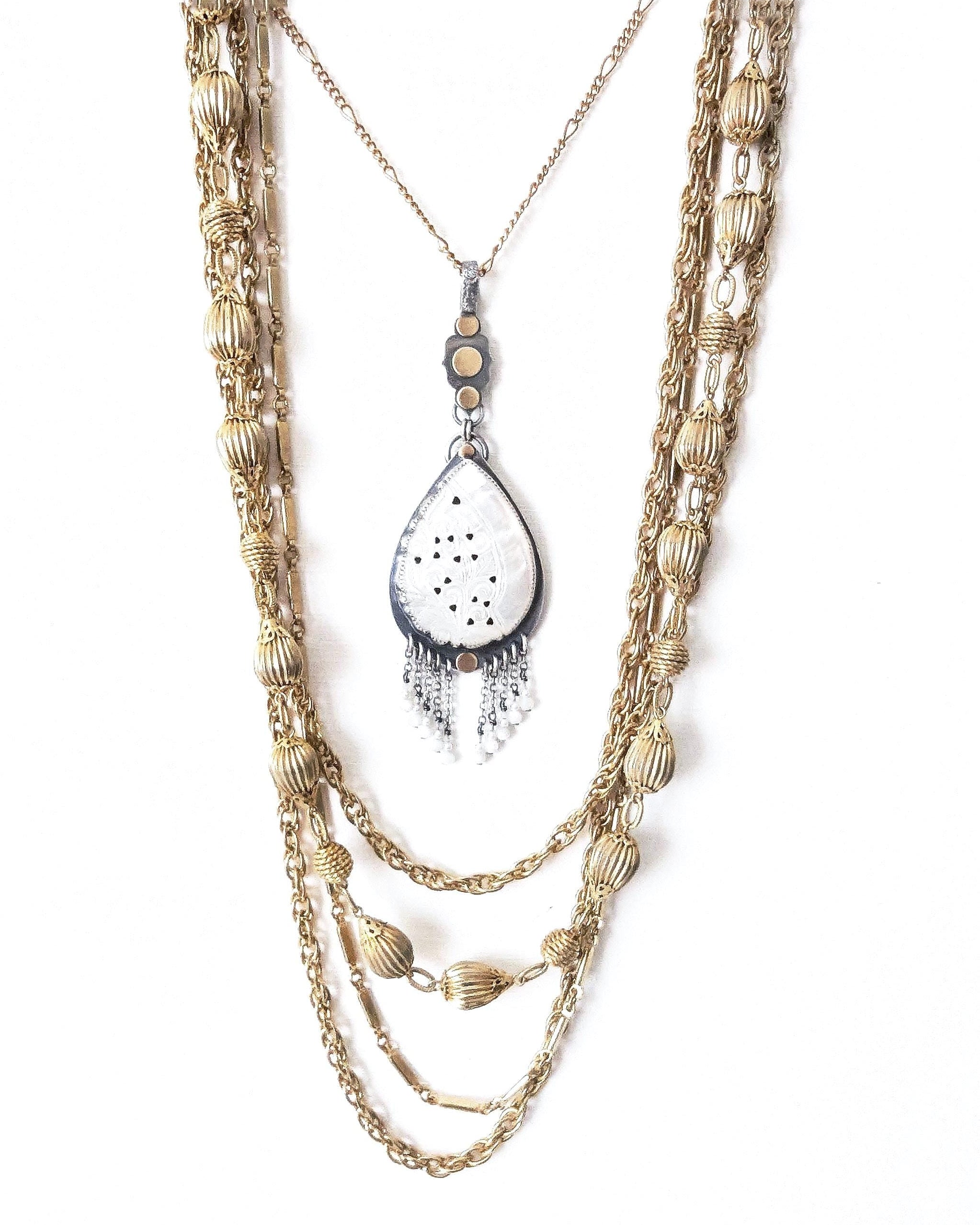 Romantic coastal pendant featuring carved mother of pearl and delicate beaded accents shown with layering necklace for styling