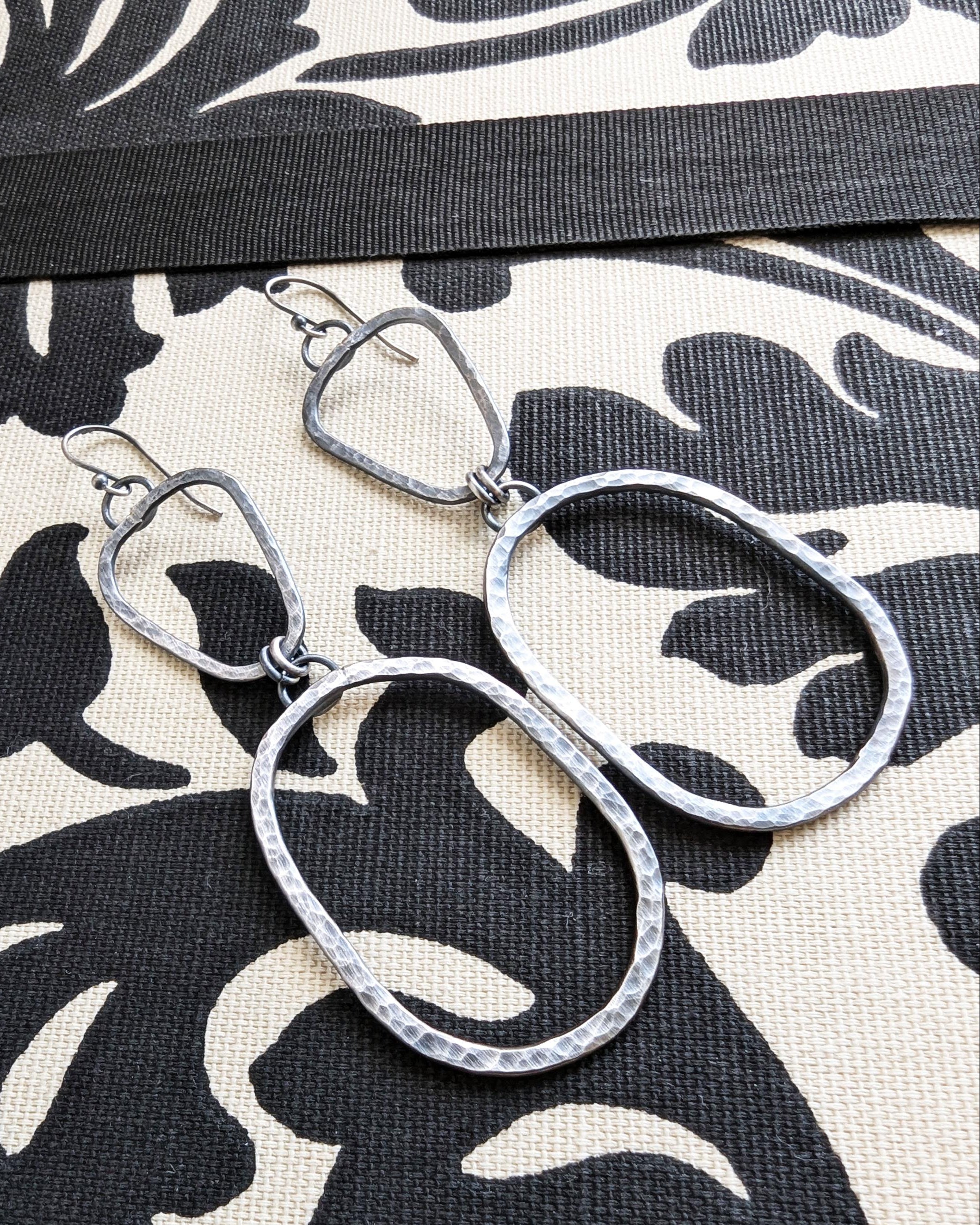 Silver hoop earrings on a black and white patterned fabric background