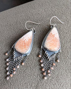 Close up of long shield statement earrings with peach scolecite mosaic stones 
