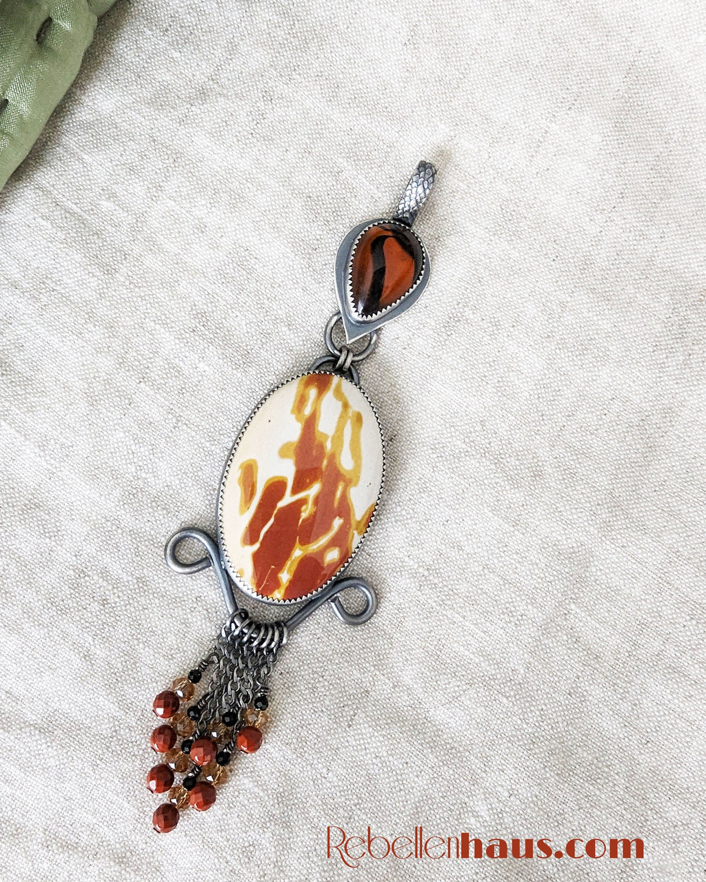 Jewelry pendant with marbled design on a textured surface.
