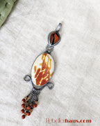 Jewelry pendant with marbled design on a textured surface.