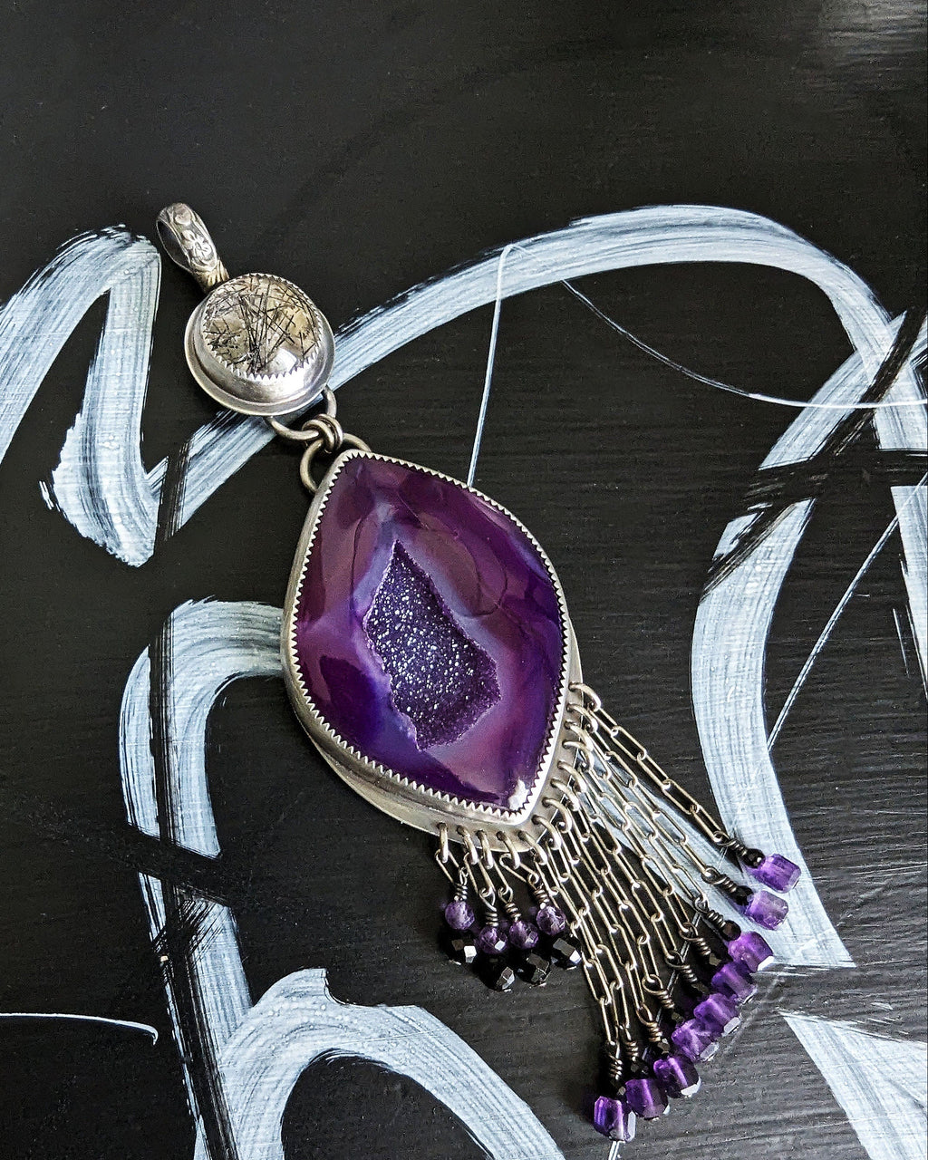 Close up of bold boho pendant with purple druzy, black tourmaline, and amethyst beads