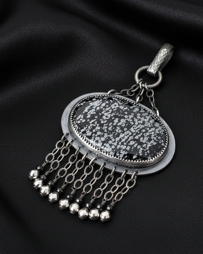 Close-up of oval snowflake obsidian showing natural black and white crystal pattern

