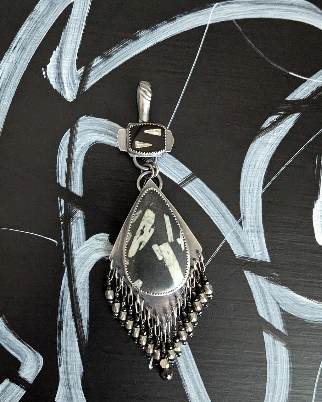 Close up of pear shaped Chinese writing stone pendant with spinel bead fringe