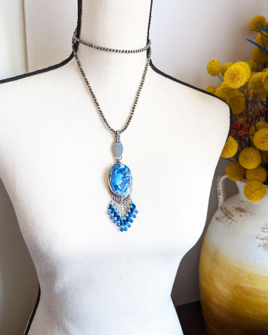 Artisan sterling silver pendant featuring azurite and lapis accents shown on bust for scale