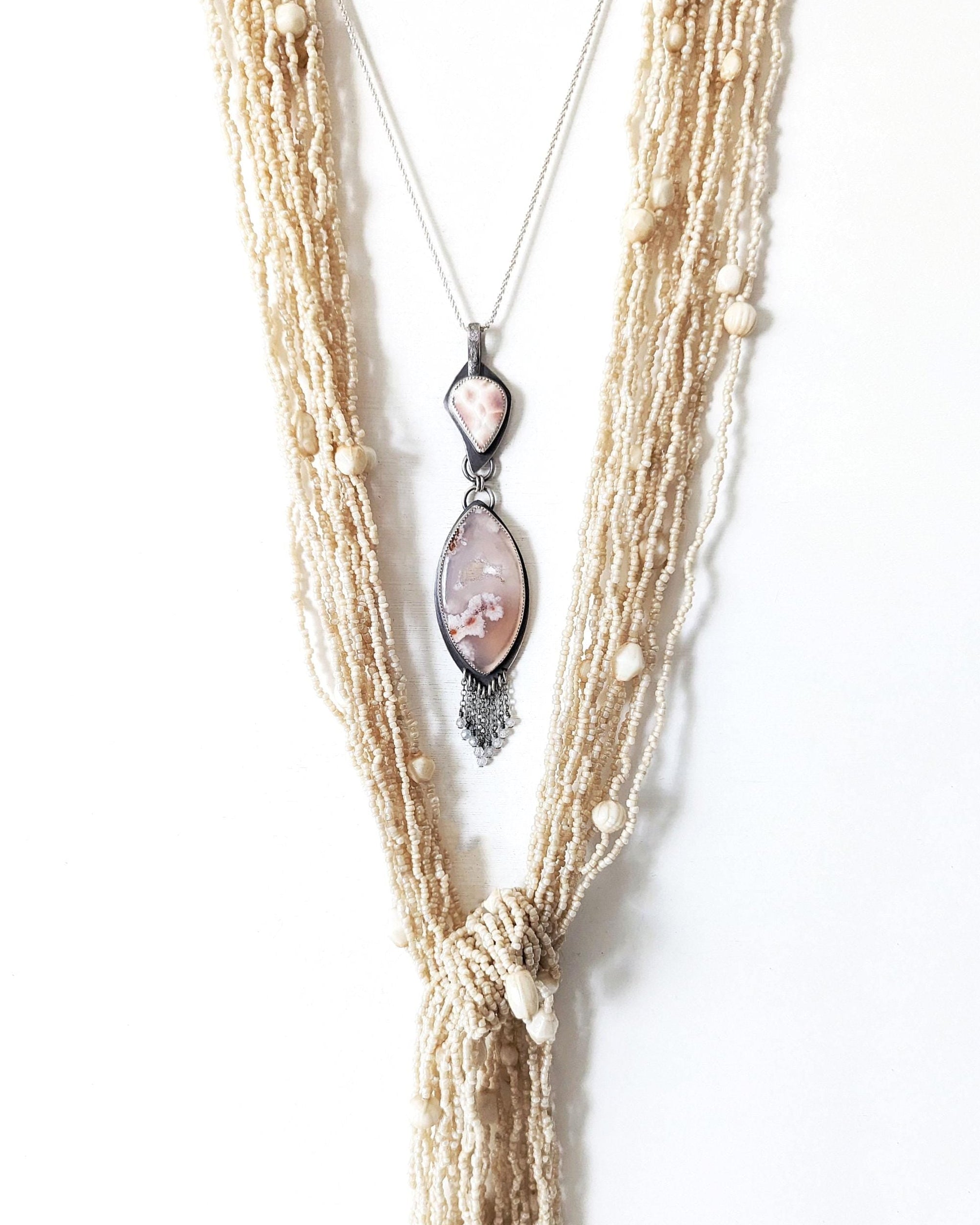 Druzy flower agate pendant with oxidized sterling silver and pearly thomsonite bail layered with a shell necklace
