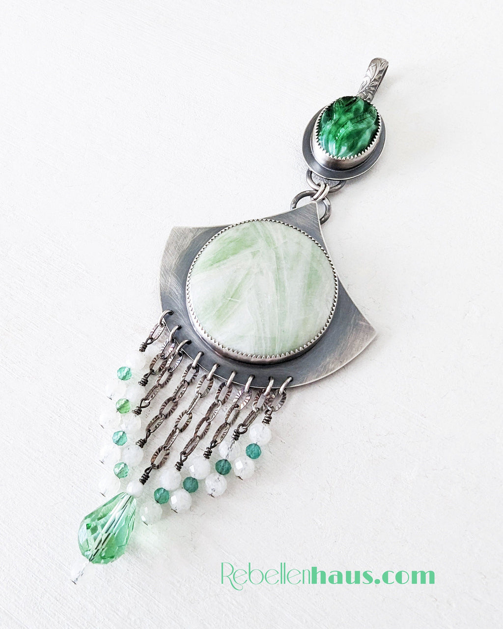 Jewelry pendant with green and white stones on a white background