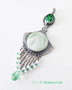 Jewelry pendant with green and white stones on a white background
