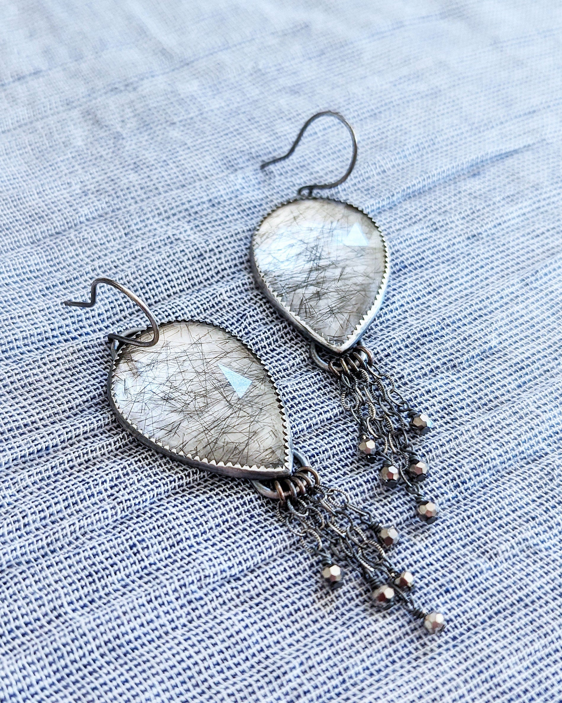 Close up of oxidized silver rutile quartz earrings with chain fringe and gunmetal crystals
