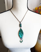 Nature inspired malachite necklace with leaf fringe and green gemstones shown on bust for scale